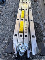 Folded aluminum articulating ladder showing hinges and rubber feet