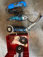 Three corded power tools laid out with discs and red metal case