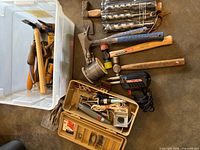Group shot of hammers, soldering gun, spool of solder, toolbox and rods