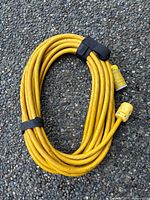 Coiled yellow heavy-duty extension cord with Velcro straps