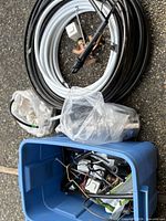 Coiled tubing, drip stake, bags of fittings and blue bin with irrigation parts