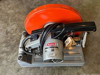 Top view of Makita model 2414 cut-off saw showing orange guard, motor label and cord