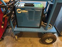 Blue Miller Millermatic Challenger 172 welder on rolling cart, cabling visible