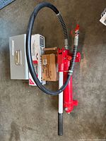 Hydraulic pump, hose, handle, steel case and boxes visible