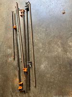 Group of long and short pipes with clamp fixtures visible