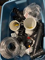 Blue tote with assorted ABS/PVC fittings, vinyl tubing and bagged parts