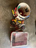Red sand-blasting tub and canvas tool bucket with assorted small tools