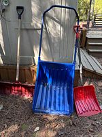Three snow removal tools leaning against shed