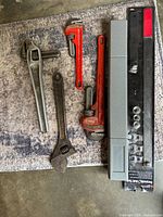 Assortment of Ridgid pipe wrench, two red pipe wrenches, adjustable wrench and torque wrench case