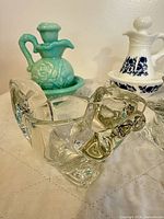 Overall view showing clear glass bulldog bottle, green milk glass pitcher, white and blue porcelain cruet decanter on saucer