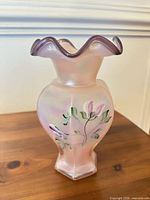 Front view of iridescent pink satin glass vase with ruffled rim and floral painting