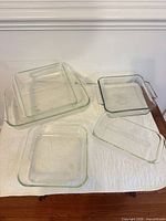 Top view of five clear glass baking dishes on white cloth