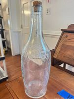 Full view of clear glass gallon bottle with cork