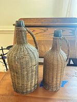 Front view of both rattan-cased bottles showing overall design and size difference