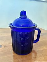 Full view of cobalt blue glass measuring cup with lid