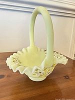 full view of pale yellow ruffled glass basket with handle