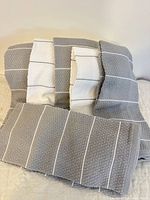 Stack of gray and white striped dish towels displayed on bed