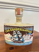 Front view of ceramic decanter showing USS Constellation graphic and labels