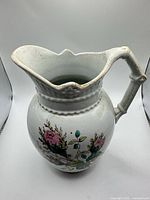 Full view of white ceramic pitcher vase with floral pattern