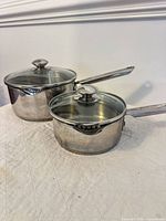 Both stainless steel saucepans with lids shown together