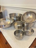 Seven stainless steel mixing bowls grouped on surface