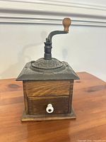 full view of grinder showing wood body, cast iron top, crank