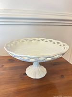 Full view of white ceramic pedestal dish on wood surface