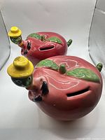 Top view of both apple piggy banks showing coin slots and worm figures