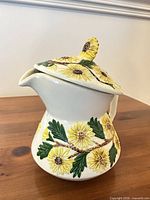 Front view of ceramic teapot with sunflower relief and lid