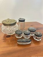 Group view of six glass jars and pumice stone showing shapes and lids