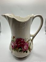 Full view of white ceramic pitcher-vase showing rose motif and handle