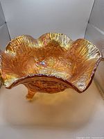 Top view of marigold carnival glass footed ruffled bowl with rose pattern
