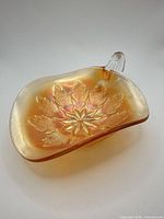 Top view showing star and leaf pressed pattern inside marigold carnival glass bowl