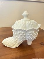 Side view of white milk glass hobnail boot candy dish with lid