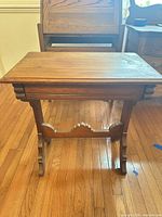 Front view of wooden side table showing overall form and trestle base