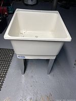 Front angled view of plastic laundry sink on legs