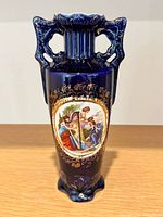 Front view showing painted cartouche, gold decoration, handles, foot
