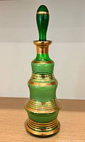 Full view of green glass decanter with stopper and gold bands