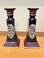 Front view of both matching porcelain candlesticks on wooden surface