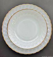 Three nested pieces showing plate, bowl, smaller plate highlighting swirl pattern and gold rim