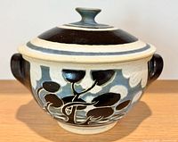 Frontal view of pot showing exterior decoration, handles and lid