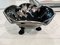 Oblique view of black glass footed bowl showing sterling silver overlay and three feet