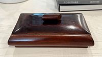 Front view of closed mahogany wooden box showing knob and beveled edges