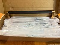 Open box showing multiple bagged black and bronze knurled handles with screws