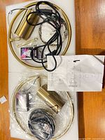 Two boxed gold wall sconces with cords, bulbs, hardware and manuals on foam trays