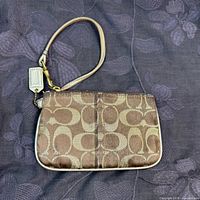 Front view of Coach Signature canvas wristlet showing monogram pattern, wrist strap attached