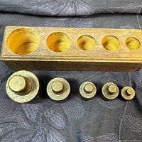 Top view of wooden block showing five recesses and two weights for size reference