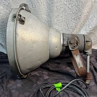 Side profile of spotlight showing cast metal body, mount and cord