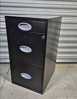 Front view of black three-drawer cabinet showing pulls and lock