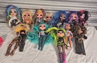 Group shot of 12 assorted fashion dolls laid on white cloth
